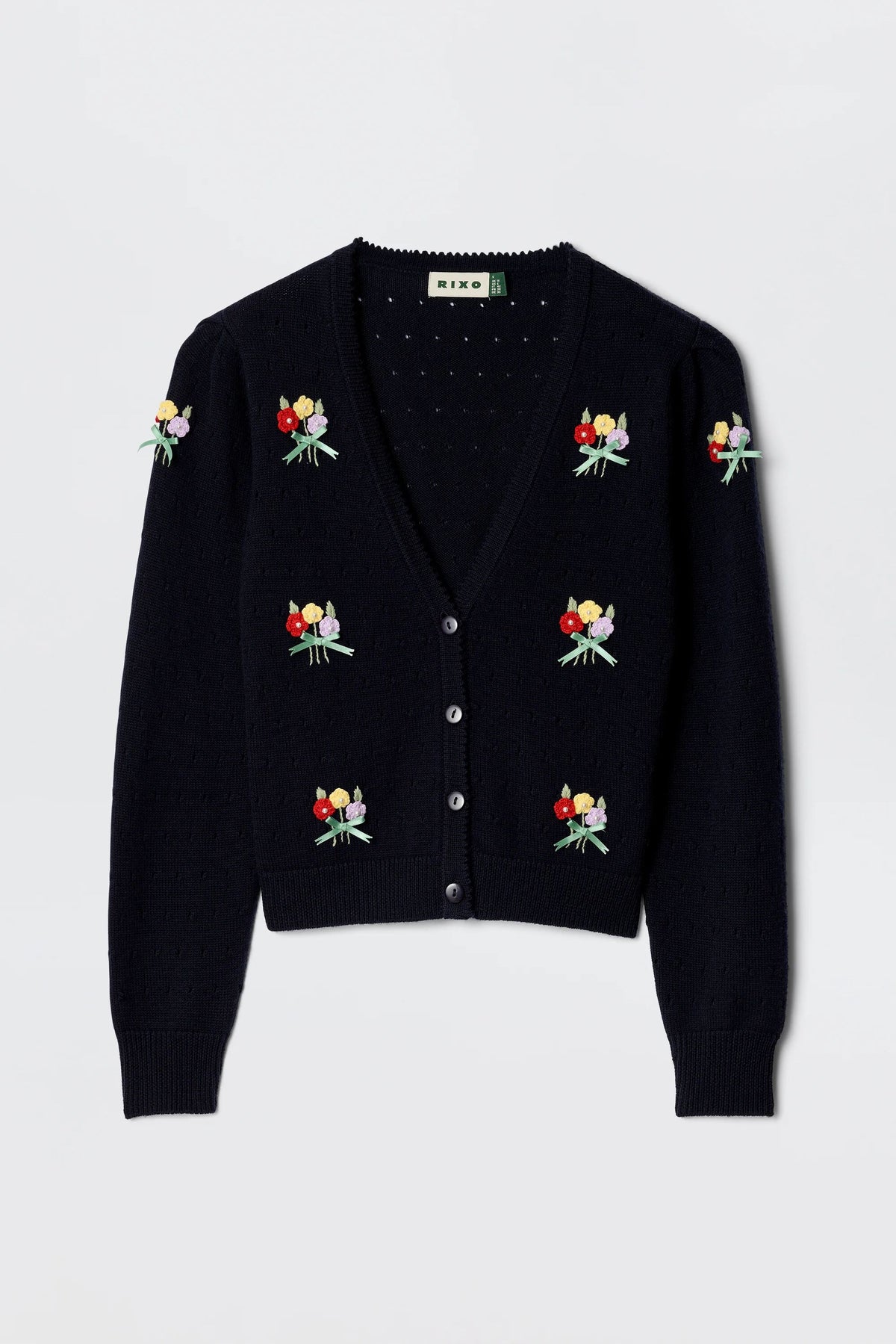 The Merinda - Floret Embroidery Deep Navy is a V-neck black cardigan with button closure, featuring colorful bouquet embroidery on the front and sleeves, a textured knit pattern, and ribbed cuffs and hem for a classic finish.