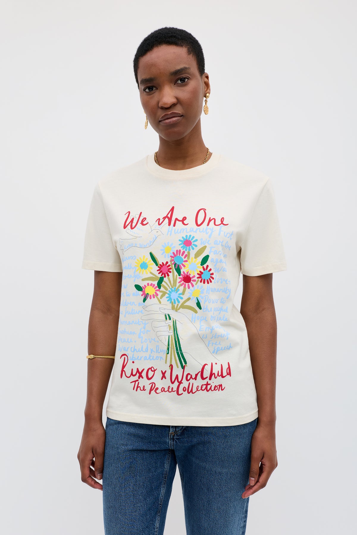 Someone wears the Charity - Rixo x War Child Cream T-shirt, inspired by the 60s, with a colorful flower vase graphic and bold red and blue "We Are One," "Rixo x War Child," and "The Peace Collection" text.