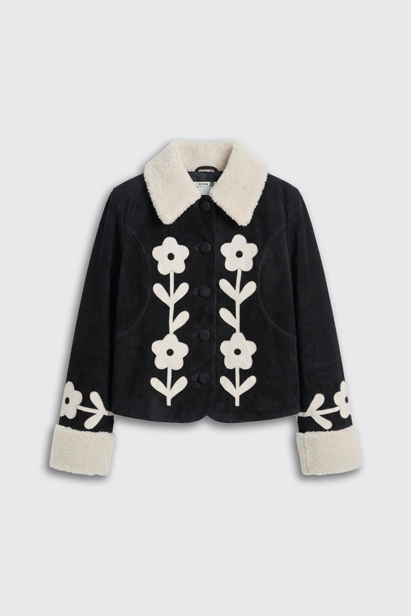 Brodie - Retro Daisy Applique Embroidery Black: A black jacket with a white faux fur collar and cuffs, adorned with large white retro daisy applique embroidery on the front and sleeves.