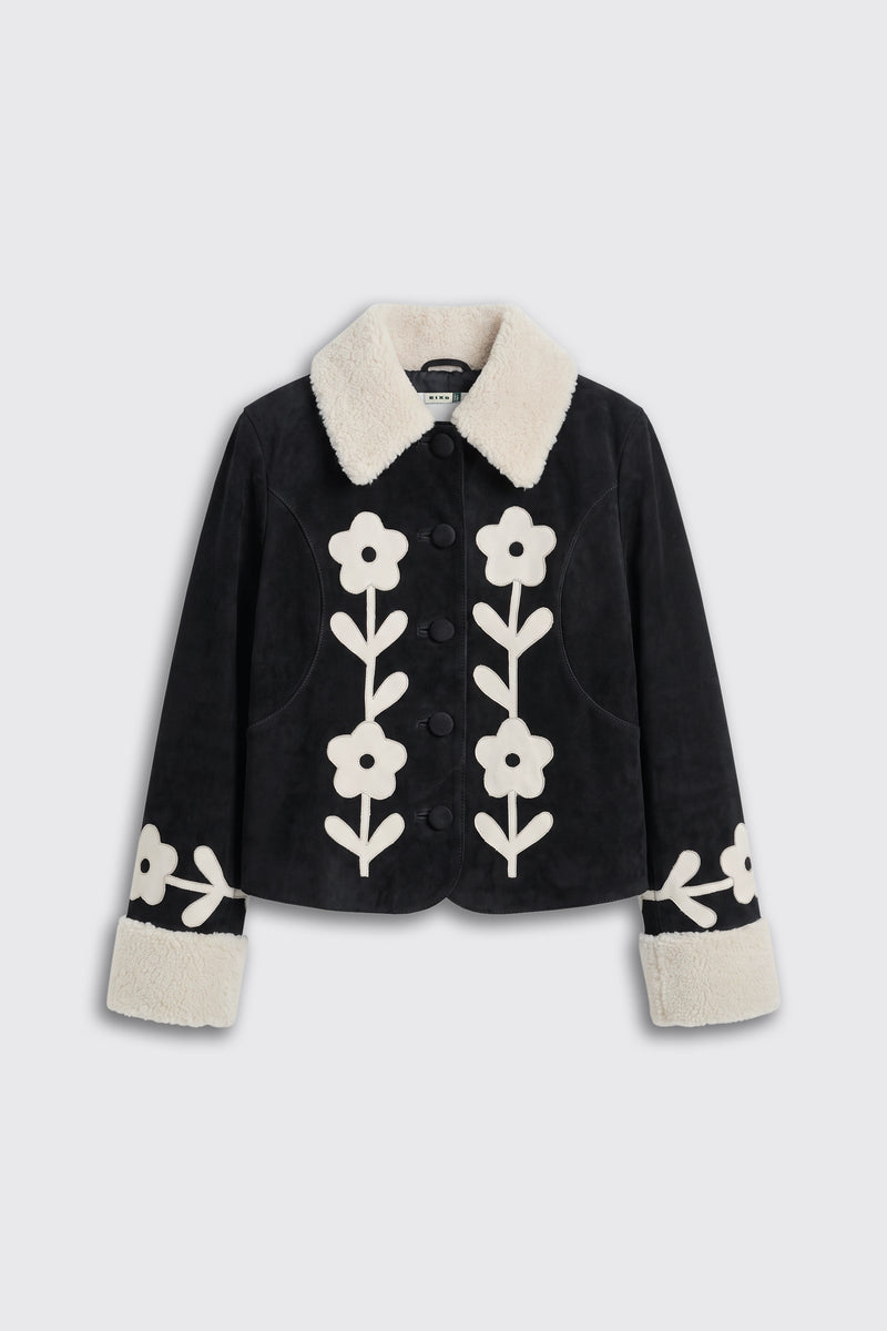 Brodie - Retro Daisy Applique Embroidery Black: A black jacket with a white faux fur collar and cuffs, adorned with large white retro daisy applique embroidery on the front and sleeves.