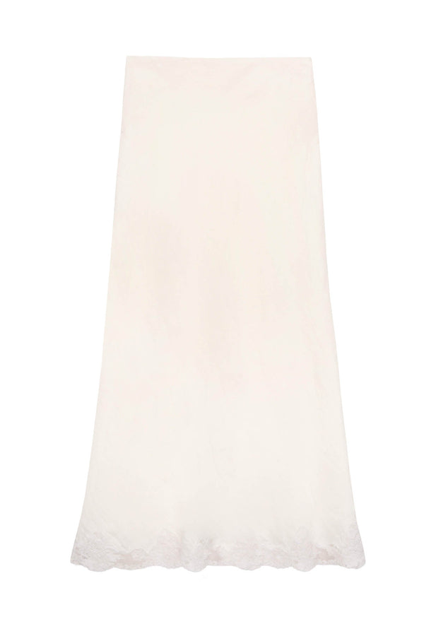 The Crystal - Cream is a long, cream midi slip skirt with a subtle floral pattern and delicate lace trim along the scalloped hem, shown against a plain white background.