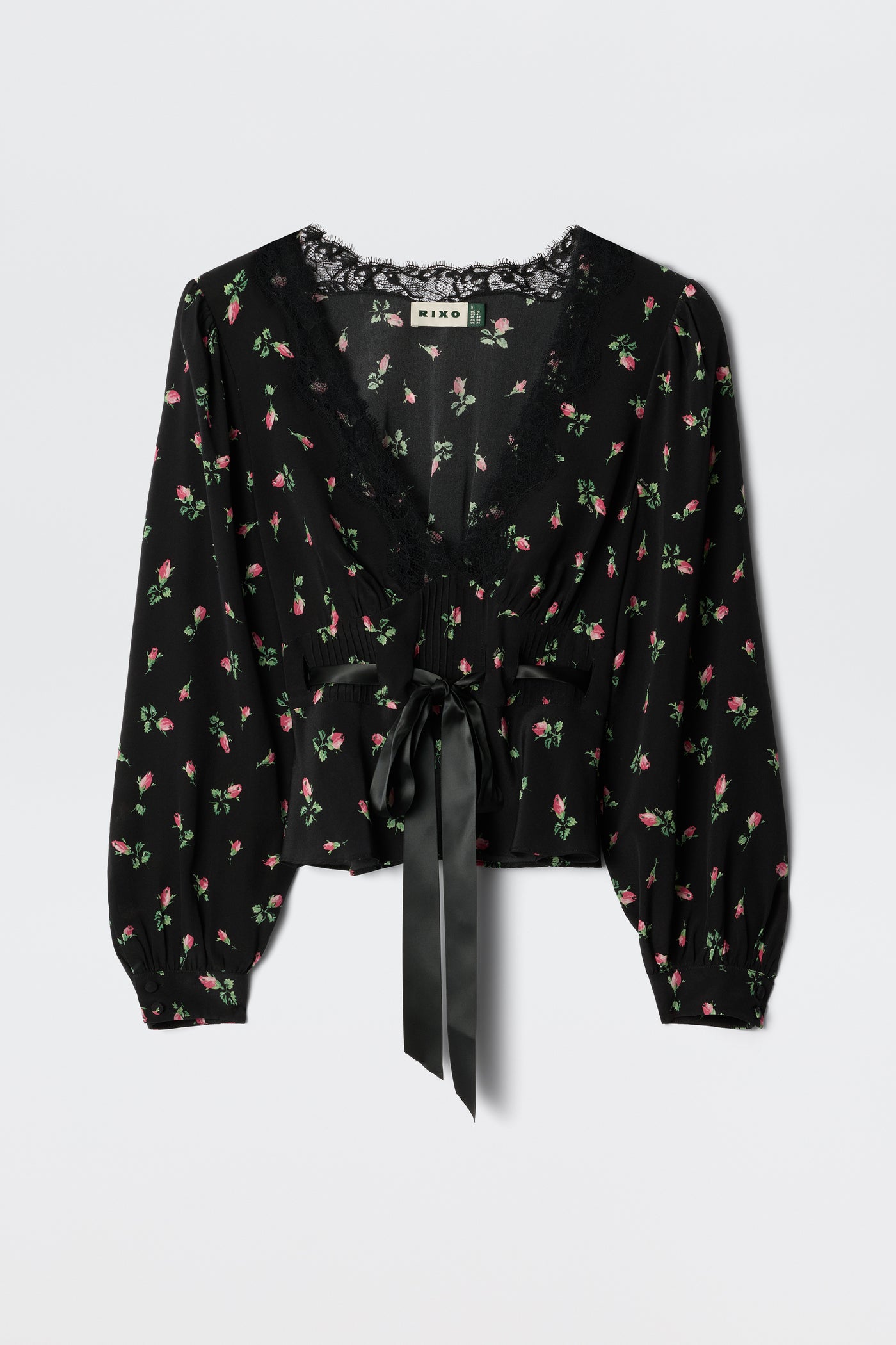 The Charis - Sienna Bud Black blouse by RIXO features black fabric with long sleeves, a delicate pink and green floral print, lace-trimmed deep V-neckline, and a wide satin ribbon bow at the waist for romantic femininity.