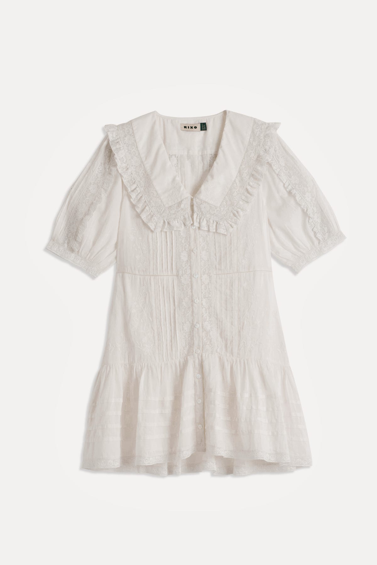 Dove - Pansy Embroidery White short-sleeve dress with delicate lace details, crafted from airy cotton-voile, featuring a ruffled collar, button front, and a tiered hem, laid flat on a white background.