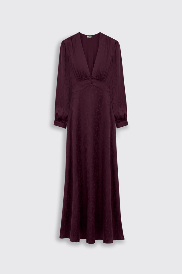 The Emory - Floral Trail Jacquard Wine is a floor-length maroon dress featuring long sleeves, a deep v-neckline, a fitted waist, and a subtle floral pattern, displayed against a light gray background.