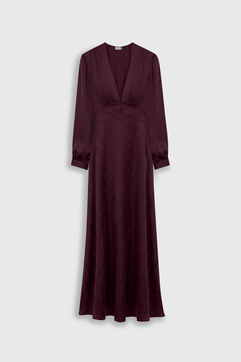The Emory - Floral Trail Jacquard Wine is a floor-length maroon dress featuring long sleeves, a deep v-neckline, a fitted waist, and a subtle floral pattern, displayed against a light gray background.