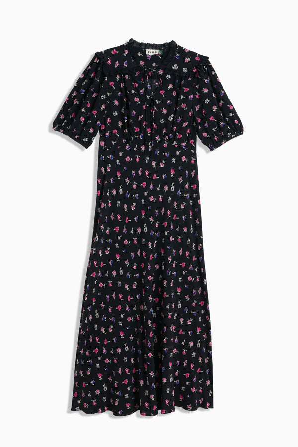 The Gwen - French Ditsy Black dress is a black midi with short sleeves, pink, white, and purple floral prints, a ruffled high neckline with tie detail—ideal for easy day-to-night wear.