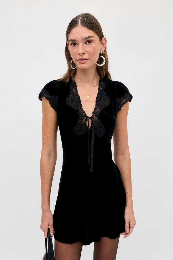 The Lacie - Black is a woman’s black velvet mini dress with a V-neckline, lace trim, and cap sleeves.