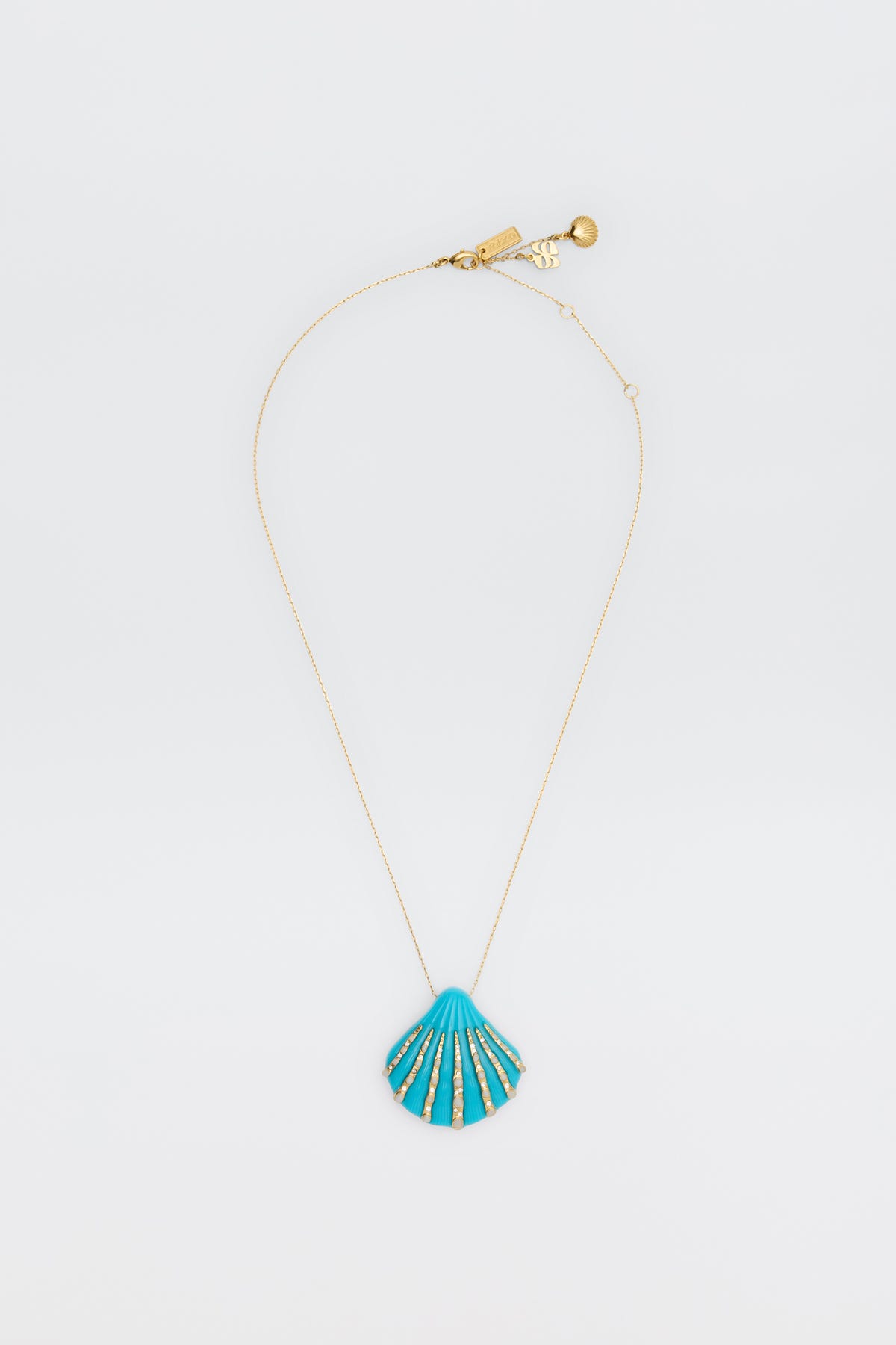 The Leanira - Turquoise necklace features a delicate gold chain with a blue seashell-shaped pendant accented in gold, shown on a plain white background.
