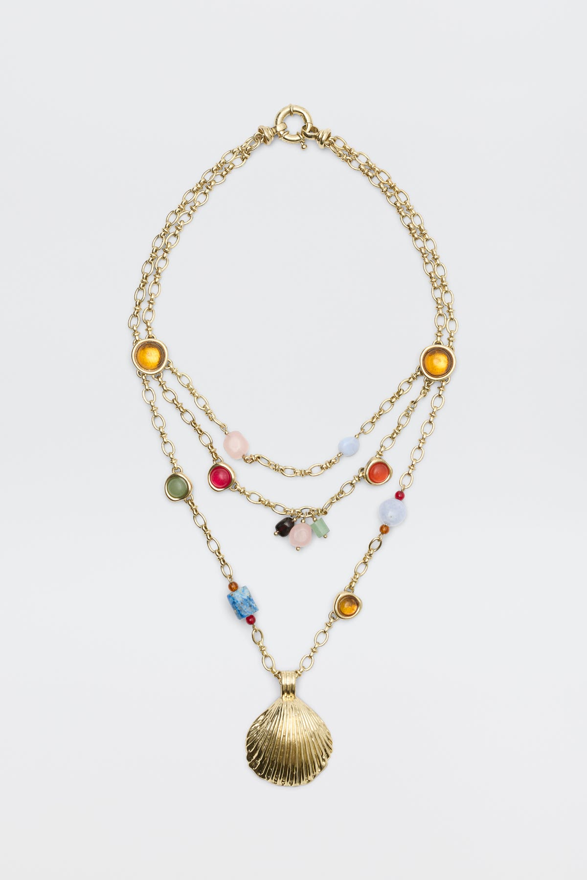 Lima - Gold necklace featuring three layered gold chains adorned with colorful beads, round yellow and green accents, and finished with a large gold seashell pendant, displayed on a plain white background.