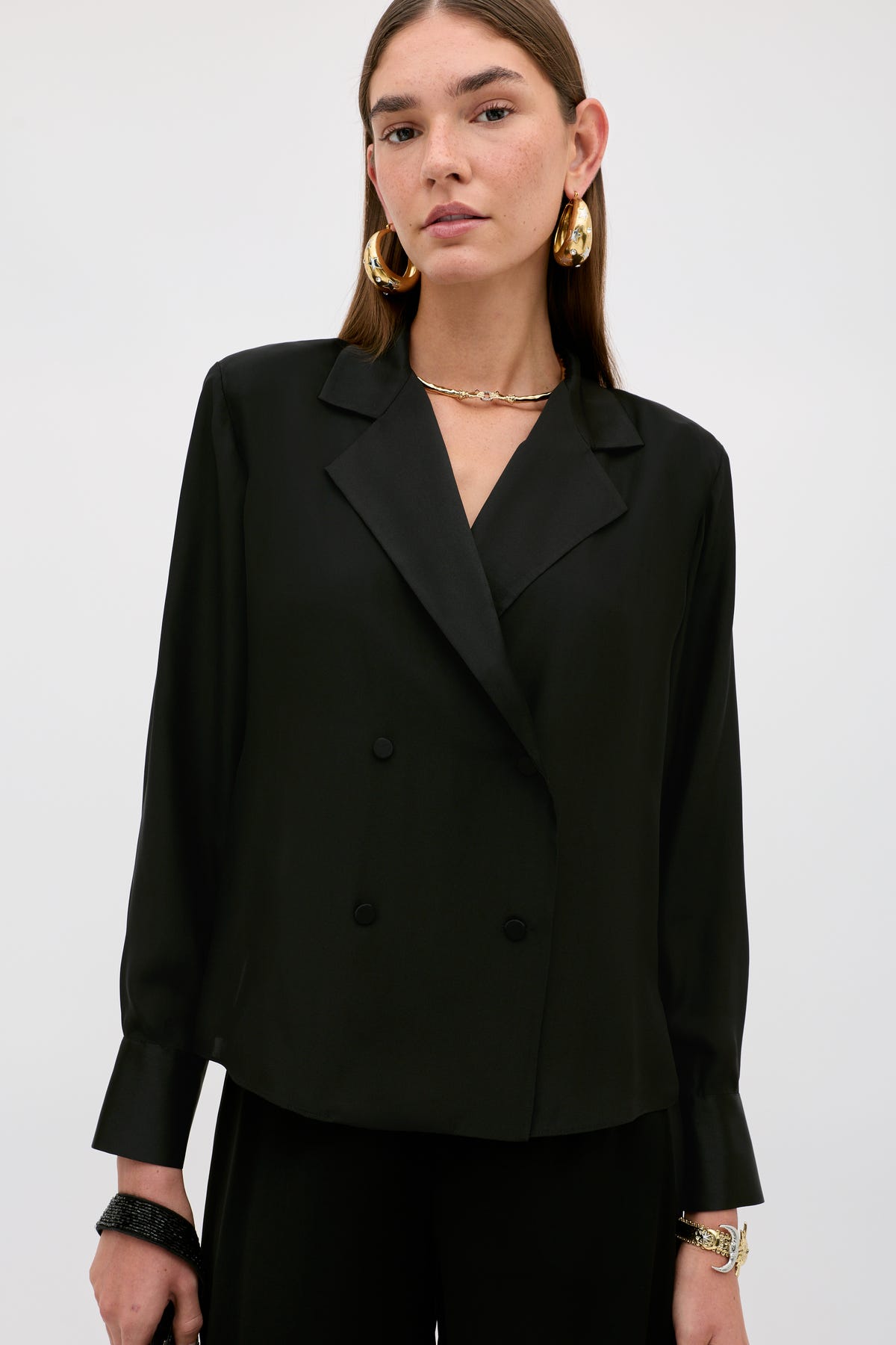 A woman wears the Lorraine - Black, a double-breasted blazer with a notched lapel and large gold hoop earrings.