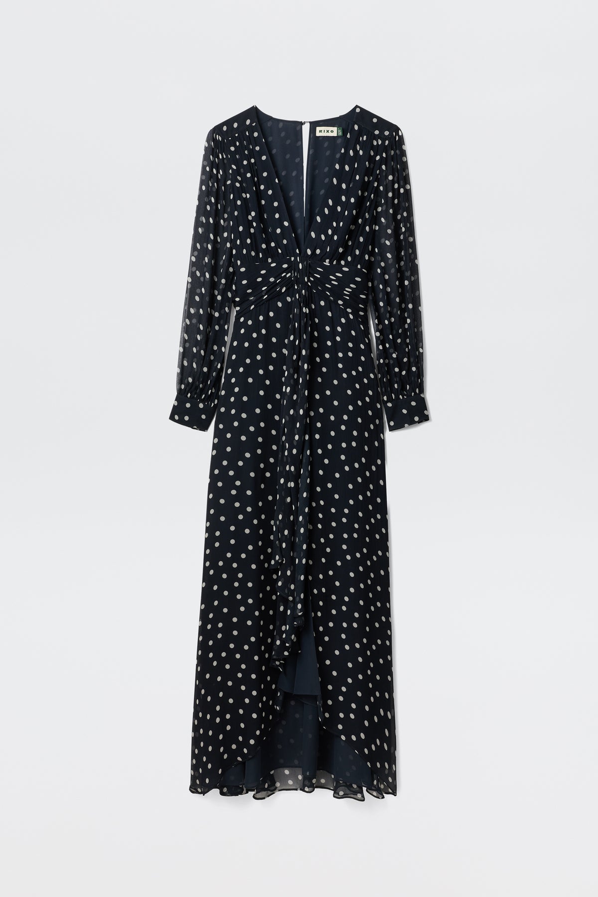 The Meera - Bohemia Spot Deep Navy is an elegant long sleeve navy gown with white polka dots, sheer sleeves, a V-neckline, and a gathered knot waist, shown on a plain light background.