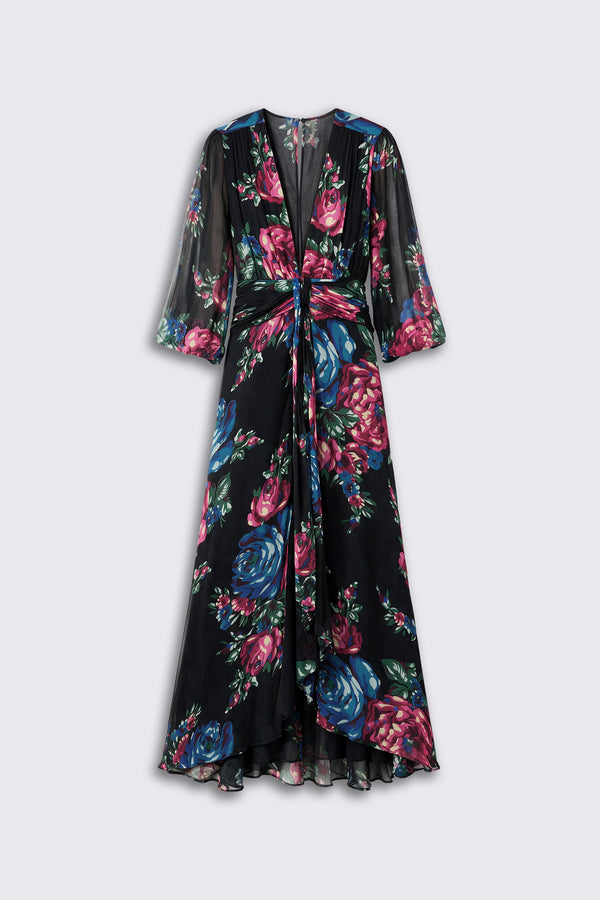 Introducing the Meera - Vintage Bouquet Black: a long, flowy black dress adorned with a vibrant floral print in shades of blue, pink, and green. This dress features a deep V-neckline, sheer sleeves, a gathered waist, and an asymmetrical hem.