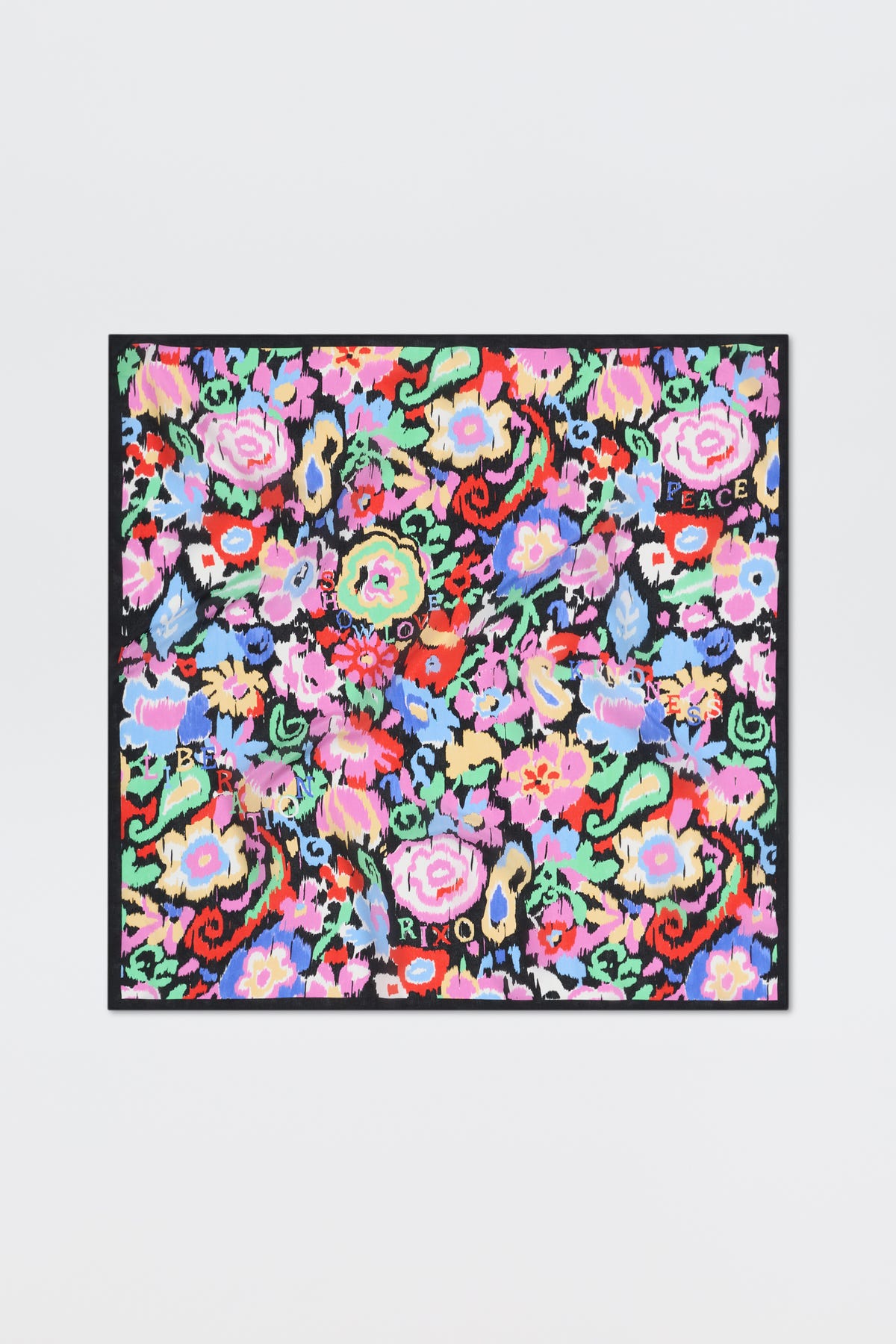 Introducing “Menno - Ikat Bloom”: a colorful square scarf featuring a vibrant floral pattern with words like LOVE, PEACE, and XOXO scattered among red, pink, blue, and green flowers on a black background.