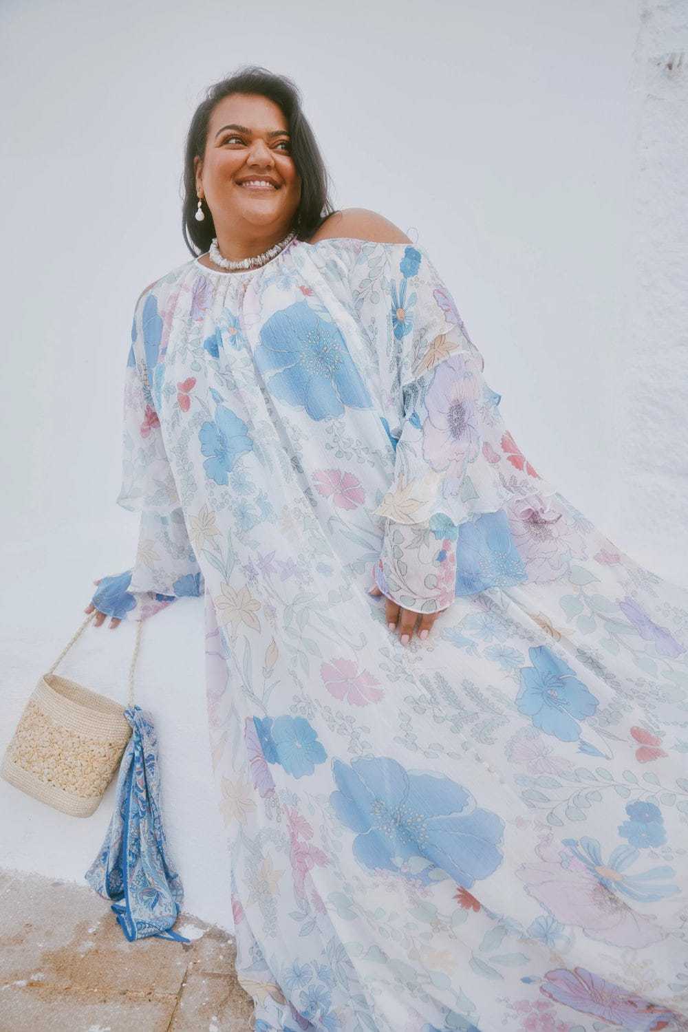 Woman wearing a floral dress with blue and pink flowers against a white background