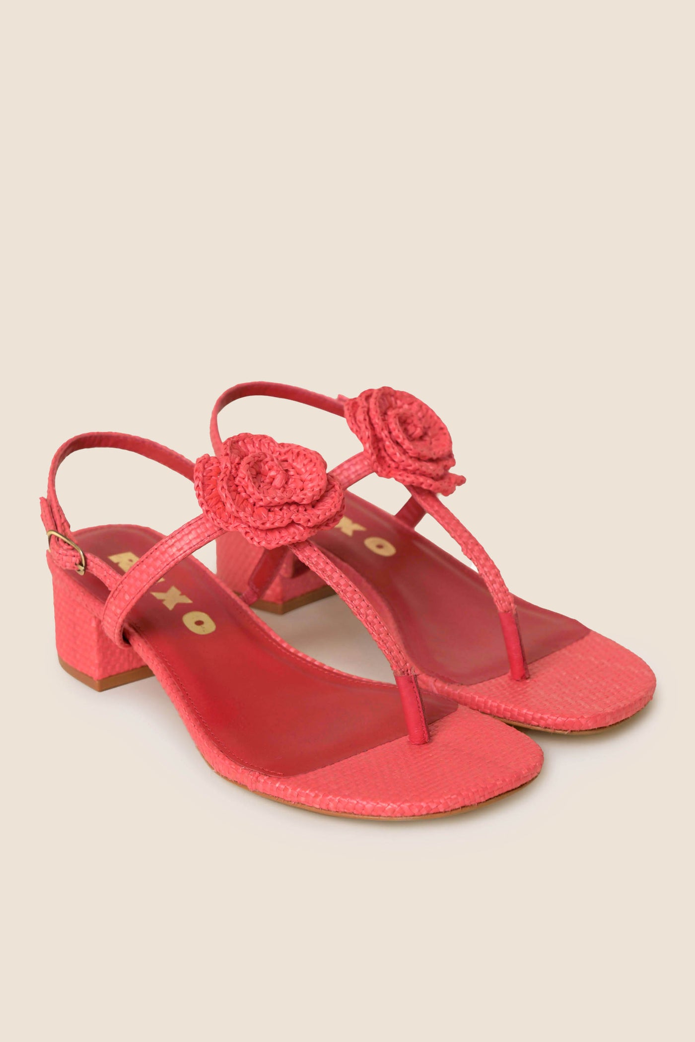 The Kasey - Red heeled sandals feature ankle straps and crochet flower accents on the front, shown against a light beige background—ideal summer footwear for special occasions.