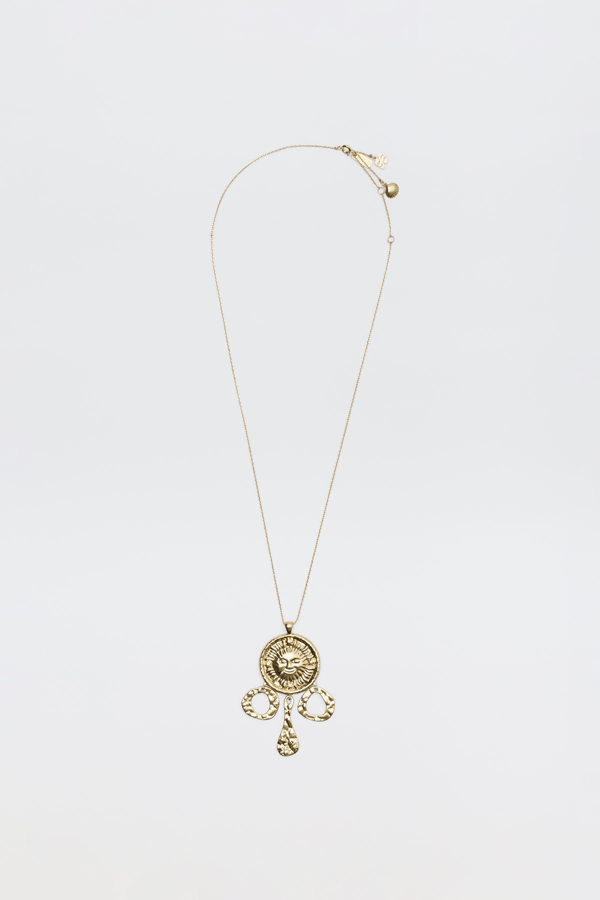 The Zahra - Gold necklace features a circular ornate pendant with intricate designs and three teardrop charms, shown against a plain white background.