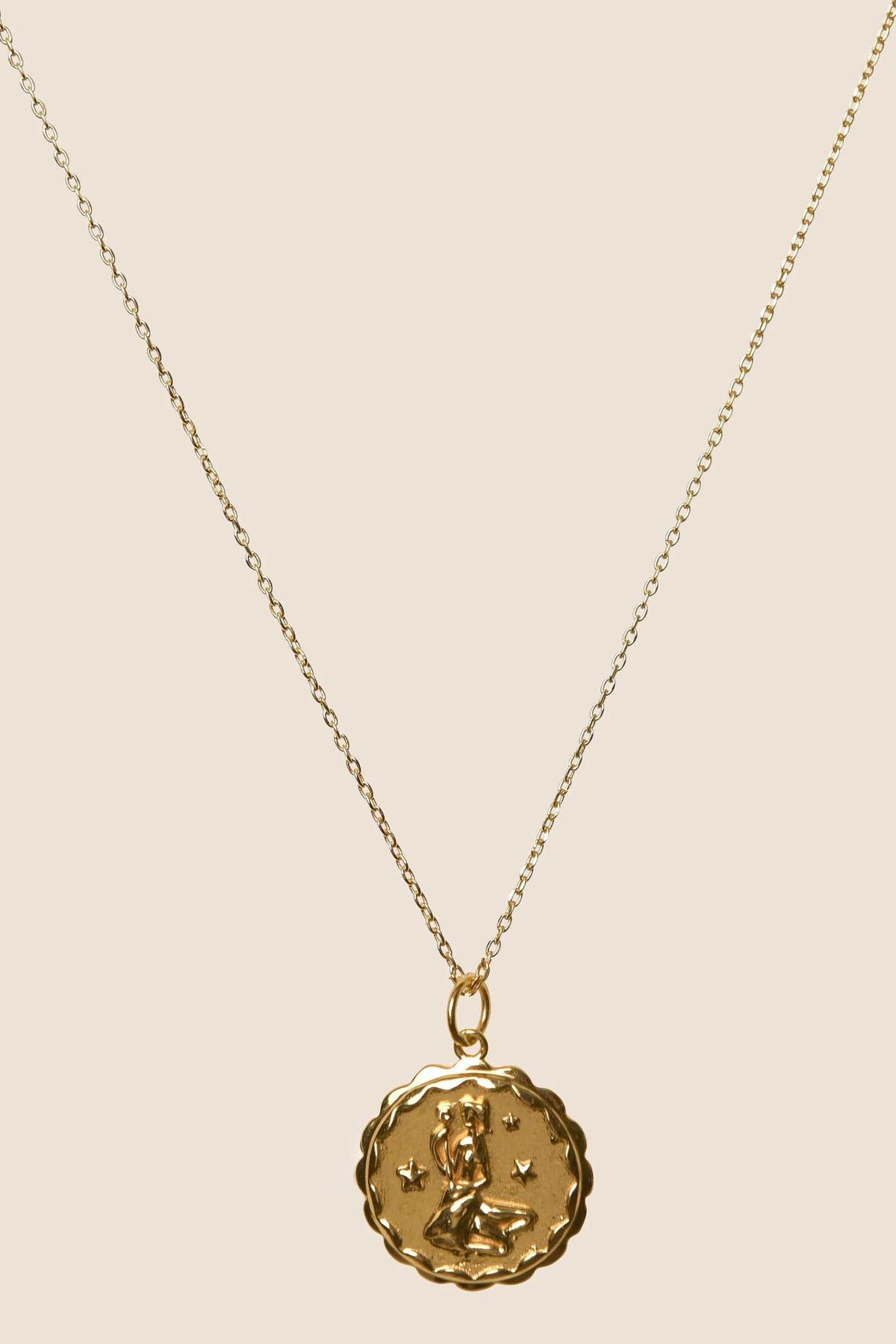 Zodiac - Virgo necklace featuring a delicate chain and an oval pendant adorned with an abstract figure and small star engravings, displayed on a plain light background.